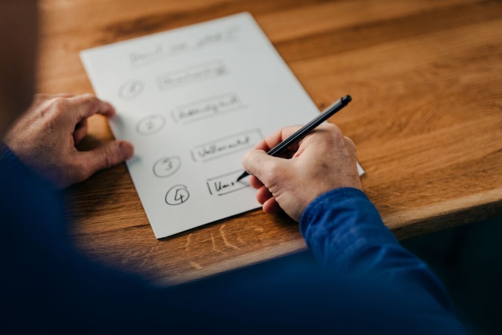 A closeup shot of a businessman writing notes on a white paper on a wooden table